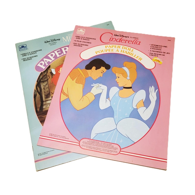 Pode incluir: Dois livros de bonecas de papel da Disney vintage. Um apresenta a Cinderela, com uma capa rosa e ilustra&ccedil;&otilde;es da Cinderela e do Pr&iacute;ncipe Encantado. O outro tem uma capa azul clara com uma imagem de uma princesa. Ambos os livros s&atilde;o rotulados como "Bonecas de papel".