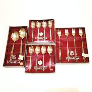May include: Three boxes of Community Silverplate cutlery. The boxes are red with gold trim and contain spoons and forks. The boxes have price tags attached.