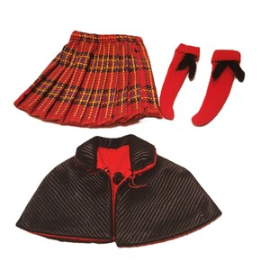 May include: A doll-sized outfit featuring a red plaid pleated skirt, red socks with black bows, and a black cape with red lining. The cape has a single button closure. The skirt has yellow and purple accents.