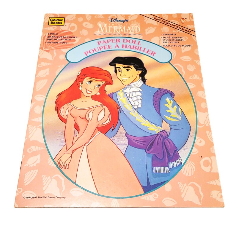 May include: A vintage Disney's The Little Mermaid paper doll set. The cover features Ariel and Prince Eric in a circular frame. The cover text includes "Paper Doll" and "Poup&eacute;e &agrave; Habiller". The set includes dolls, precut fashions, and accessories.