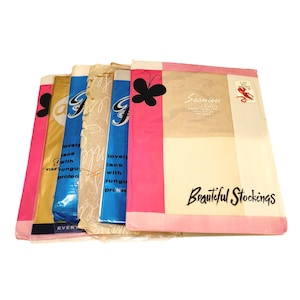 May include: A stack of five vintage packages of stockings. The top package is pink and white with the text "Seamless First Quality 100% Nylon" and "Beautiful Stockings". The other packages are blue and white with the text "lovely lace with rungul protec" and "every".