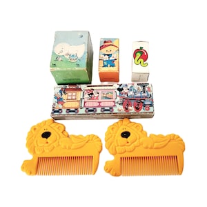 May include: A set of vintage children's toys, including a train, a lion-shaped comb, and several small boxes with illustrations of a ghost, a farmer, and a worm. The boxes are all in various shades of blue, green, red, and yellow.