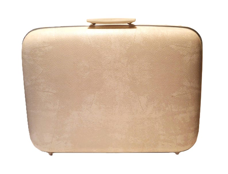 May include: A vintage, rectangular suitcase in a light beige color. The suitcase has a textured surface, rounded corners, and a small, light-colored handle on top. The suitcase has small feet on the bottom.