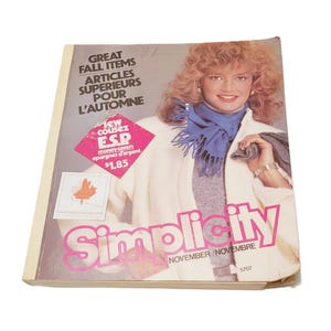 May include: A Simplicity sewing pattern catalog for November, featuring a person wearing a white jacket, a grey sweater, and a blue fringed scarf. The cover includes the text Great Fall Items, Articles Superieurs Pour L'Automne, and Sew Cousez E.S.P.
