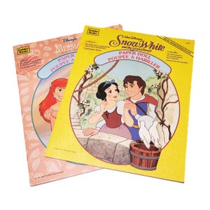 May include: Two vintage Disney Golden Books paper dolls. One features Ariel from The Little Mermaid, the other Snow White and the Seven Dwarfs. Both books have illustrations of the characters and include precut fashions and accessories.