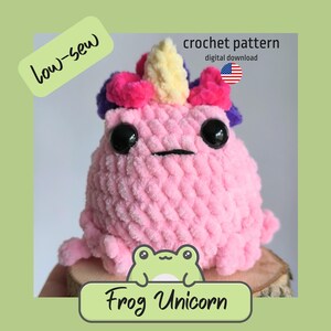 May include: A pink crocheted frog toy with large black eyes and a small mouth. It has a unicorn horn and a crown of pink, purple, and yellow. The text "Frog Unicorn" is below the frog. The image also includes the text "low-sew" and "crochet pattern digital download".