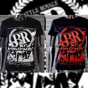 May include: Two black t-shirts with a white and red graphic print. The graphic features the text "Battle Royale" and "BR" in a circle with a laurel wreath. The text "Tval Fam" and "バトル・ロワイアル" are also included in the graphic. The text "5th December 2000" and "Y1800 on the door" are printed below the graphic.