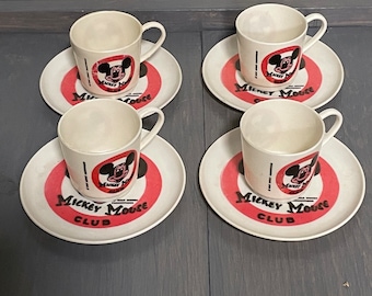 Peut inclure: Quatre tasses et soucoupes assorties de couleur crème. Chaque soucoupe présente un anneau rouge avec les mots "Mickey Mouse Club" et un dessin de Mickey Mouse. Les tasses ont un dessin de Mickey Mouse assorti.