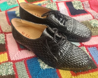 May include: A pair of black woven leather lace-up shoes with the brand name "M. John" on the insole.