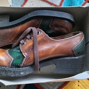 May include: Brown leather shoes with green accents and laces. The shoes have a chunky platform sole.
