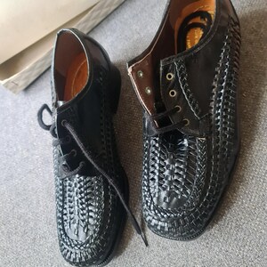 May include: A pair of black leather shoes with a woven design. The shoes have laces and a rounded toe.
