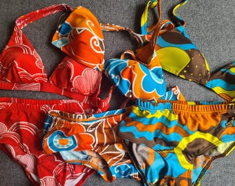 Puede incluir: Una colección de bikinis coloridos con varios estampados. La ropa de baño incluye tops halter y braguitas en rojo, naranja, azul, marrón y amarillo. Los estampados incluyen diseños florales y abstractos, perfectos para un día de verano en la playa.