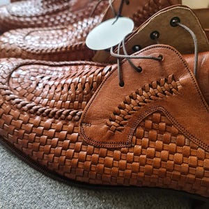 May include: A pair of brown leather shoes with a woven pattern. The shoes have laces and are made of high-quality material.