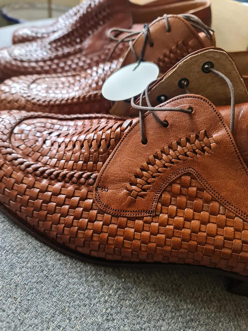 May include: A pair of brown leather shoes with a woven pattern. The shoes have laces and are made of high-quality material.