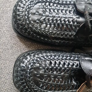 May include: A pair of black leather shoes with a woven design. The shoes have a lace-up closure and a rounded toe.