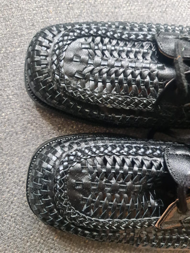 May include: A pair of black leather shoes with a woven design. The shoes have a lace-up closure and a rounded toe.