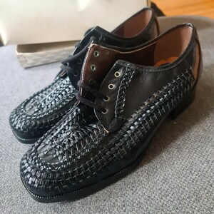 May include: A pair of black leather shoes with a woven pattern. The shoes have a lace-up closure and a rounded toe.