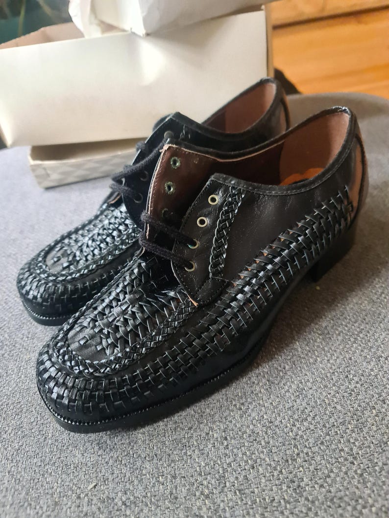 May include: A pair of black leather shoes with a woven pattern. The shoes have a lace-up closure and a rounded toe.