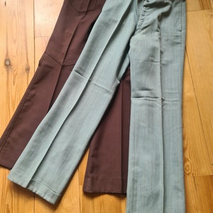 May include: Two pairs of trousers, one brown and one light blue with white stripes. Both trousers have a wide leg style.