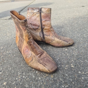 Può includere: Stivaletti con motivo a pelle di serpente nei toni del marrone, beige e marrone chiaro. Gli stivali hanno una chiusura con cerniera e un tacco basso. Gli stivali sono realizzati in un materiale strutturato.