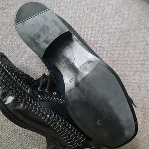 May include: Black leather shoes with a woven pattern and a black rubber sole. The sole has the text "Made in Italy" and the number "37" printed on it.