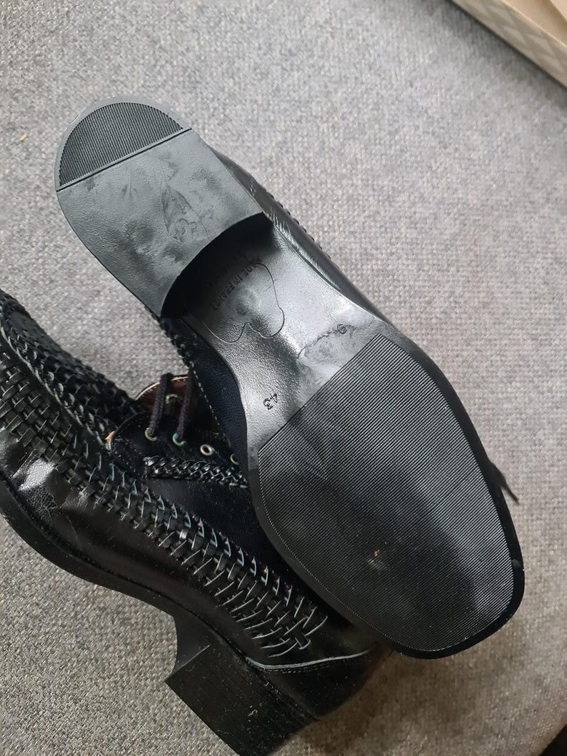 May include: Black leather shoes with a woven pattern and a black rubber sole. The sole has the text "Made in Italy" and the number "37" printed on it.