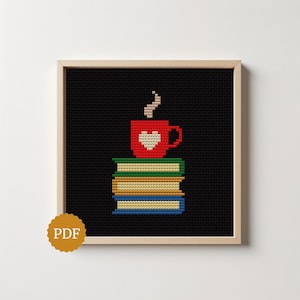 May include: A cross-stitch pattern in a light wood frame featuring a stack of three books in green, tan, and blue, topped with a red mug containing a white heart and steam. A circular gold badge with the text PDF is in the bottom left corner.