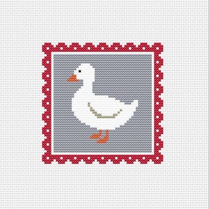May include: A cross-stitch design featuring a white goose with an orange beak and feet, set against a gray background. The design is framed by a red border with white polka dots, all on a white fabric background.