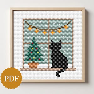 May include: Cross-stitch art of a black cat silhouette sitting in a window, with a Christmas tree and string lights. The window has a snowy background. The artwork is in a wooden frame, with a PDF logo.