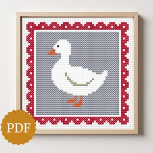 May include: A framed cross-stitch pattern featuring a white goose with orange feet and beak, set against a gray background. The design is framed by a red border with white dots. The image is labeled "PDF".