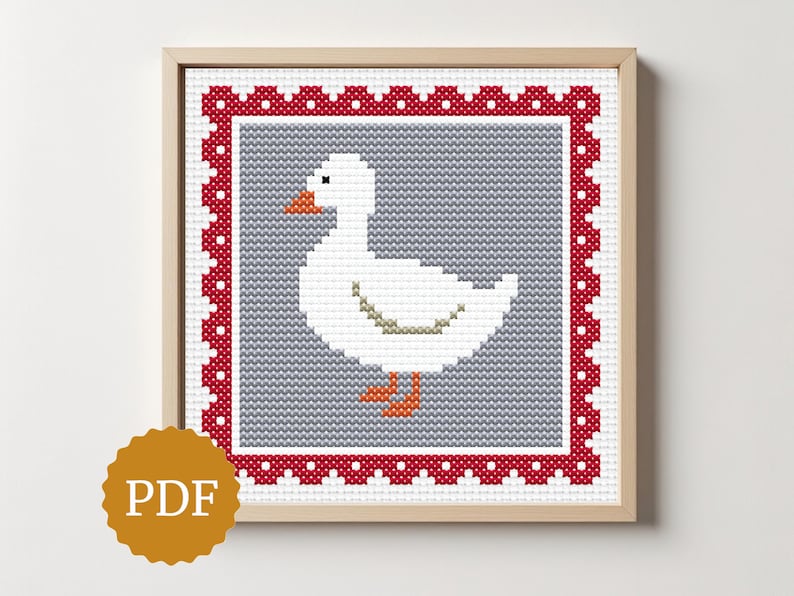 May include: A framed cross-stitch pattern featuring a white goose with orange feet and beak, set against a gray background. The design is framed by a red border with white dots. The image is labeled "PDF".