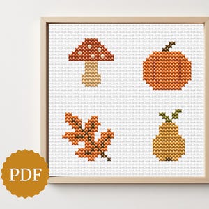 May include: Cross-stitch artwork in a wooden frame, depicting autumn motifs. The design includes a mushroom, pumpkin, leaf, and pear, in orange, brown, and yellow hues. The image also includes a PDF logo.