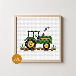 May include: A cross-stitch pattern featuring a green tractor with yellow wheels and a black cab, set against a white grid background. The tractor is positioned on a brown ground line with small green tufts of grass and a wisp of blue exhaust smoke.
