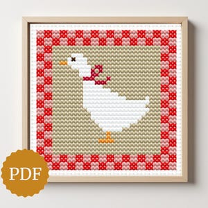 May include: A framed cross-stitch pattern featuring a white goose with a red bow, set against a tan background and a red and white checkered border. The image is in a wooden frame, with a PDF logo in the lower left corner.