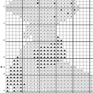 May include: A cross-stitch pattern chart with a grid of squares. The design features various symbols, including circles, diamonds, triangles, and stars, in black, white, and other colors. The chart is for a craft project.