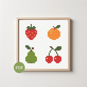 May include: A framed cross-stitch pattern featuring four fruit designs on white Aida cloth. The design includes a red strawberry, an orange citrus fruit, a green pear, and two red cherries, all with green stems. A green circular PDF icon is visible.