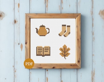 May include: A cross stitch pattern in a wooden frame featuring four distinct motifs: a golden teapot, a pair of tan socks, an open book with dark brown pages, and a golden oak leaf. A circular gold badge with the text PDF is in the corner.