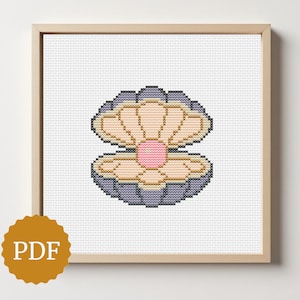 Può includere: Schema a punto croce di una conchiglia aperta con una perla rosa. Il guscio è nei toni del grigio, beige e rosa, incorniciato in una cornice di legno chiaro. Il logo PDF si trova nell'angolo in basso a sinistra.