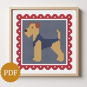 May include: Cross-stitch artwork of a dog wearing a blue shirt, set against a gray background. The design is framed with a red and white border and presented in a wooden frame. A PDF icon is in the lower left corner.