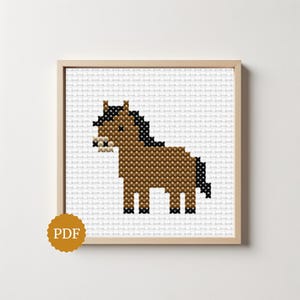 May include: A cross-stitch pattern featuring a brown horse with a black mane and tail, set against a white grid background. The design is framed in a light wood square frame, and a circular gold badge with the text PDF is in the bottom left corner.