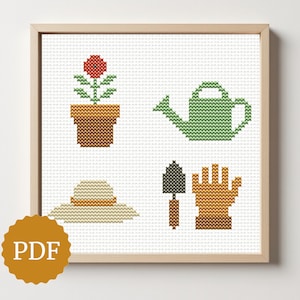 May include: Cross-stitch art print featuring gardening tools: a flower in a pot, a watering can, a sun hat, a trowel, and a gardening glove. The artwork is framed in a light wood frame. A PDF logo is in the lower left corner.