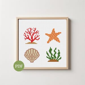 May include: A framed cross-stitch artwork featuring four marine-themed designs: a red coral, an orange starfish, a beige seashell, and green seaweed. The artwork is in a wooden frame and includes a PDF icon.