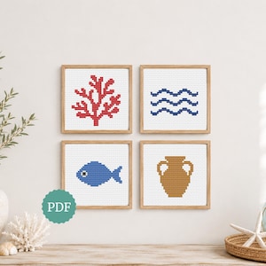 May include: Four framed cross-stitch artworks with nautical themes. The designs include a red coral, blue waves, a blue fish, and a brown amphora. The artworks are displayed on a white wall above a wooden surface, with decorative elements.