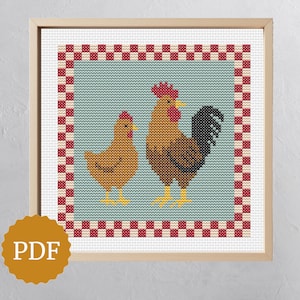 Puede incluir: Obra de arte de punto de cruz con un gallo y una gallina en tonos marrones, rojos y amarillos. El diseño está sobre un fondo azul claro con un borde a cuadros rojo y blanco, enmarcado en madera clara. Un icono PDF está en la esquina inferior izquierda.
