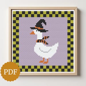 May include: Cross-stitch artwork of a goose wearing a witch hat and scarf, set against a lavender background. The goose has orange feet and beak. The artwork is framed with a checkered border of black, green, and yellow squares. The image includes a PDF logo.