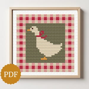 Könnte beinhalten: Gerahmtes Kreuzstichmuster mit einer weißen Gans mit roter Schleife auf grünem Hintergrund. Das Design wird von einem rot-cremefarbenen Vichymuster umrandet. Das PDF-Symbol ist unten links sichtbar.