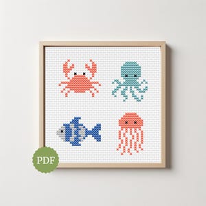 Puede incluir: Un patrón de punto de cruz enmarcado con cuatro criaturas marinas: un cangrejo, un pulpo, un pez y una medusa. El cangrejo es coral, el pulpo es turquesa, el pez es azul y la medusa es coral. El marco es marrón claro.