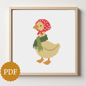 May include: Cross-stitch pattern of a duck wearing a red polka-dot bonnet and a green scarf. The duck is beige with orange feet and beak. The artwork is framed in a light wood frame and includes a PDF icon.