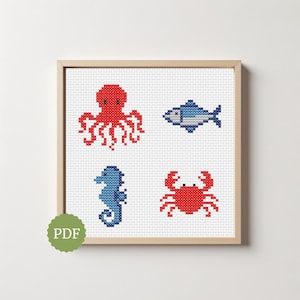 Puede incluir: Un patrón de punto de cruz enmarcado con cuatro criaturas marinas: un pulpo rojo, un pez azul, un caballito de mar azul y un cangrejo rojo. La obra de arte está sobre un fondo blanco y dentro de un marco de madera. Un icono PDF está en la esquina inferior izquierda.
