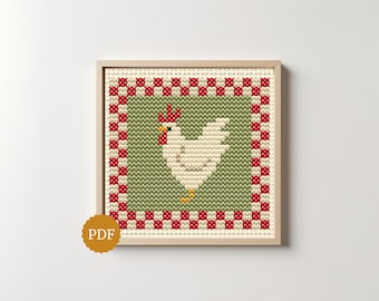 May include: A square cross-stitch pattern featuring a white chicken with a red comb and wattle, centered on a sage green background. The design is framed by a red and white checkered border and is presented within a light wood frame.